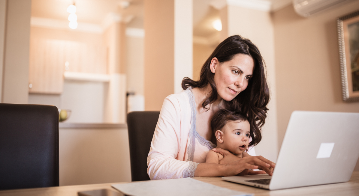 mother working on computer while baby is sitting on lap 
