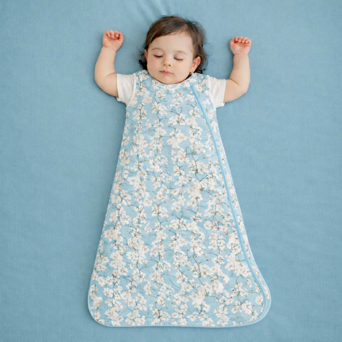 Child wearing a cherry blossom floral 
sleep bag on a blue background