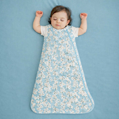 Child wearing a cherry blossom floral 
sleep bag on a blue background