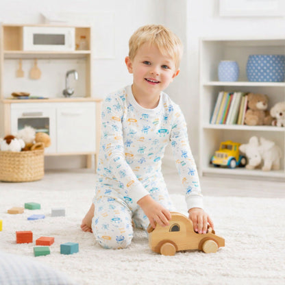 Child playing with a wooden toy car in a room with shelves and toys in norani baby pajamas