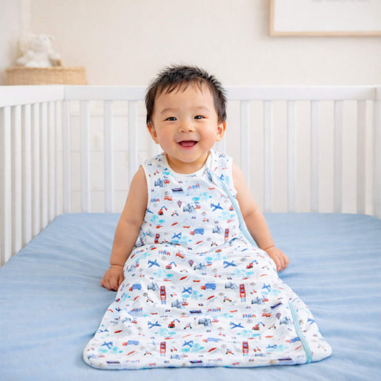 Child wearing a transportation print sleep sack by norani baby called one and done sleep sack sitting in a crib.