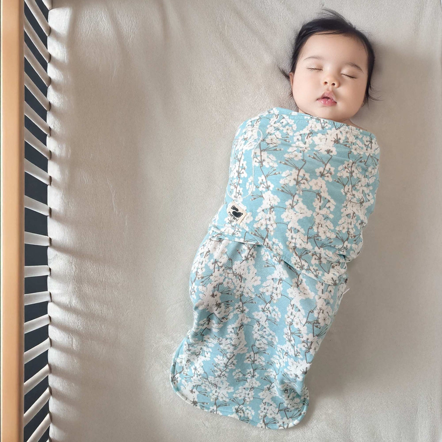 Baby swaddled in a floral blanket on a bed