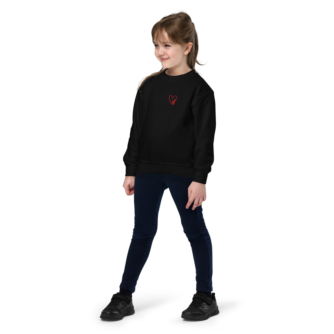 Girl wearing a black crewneck sweatshirt with a subtle embroidered heart on the chest, styled for a clean, cozy, everyday look.
