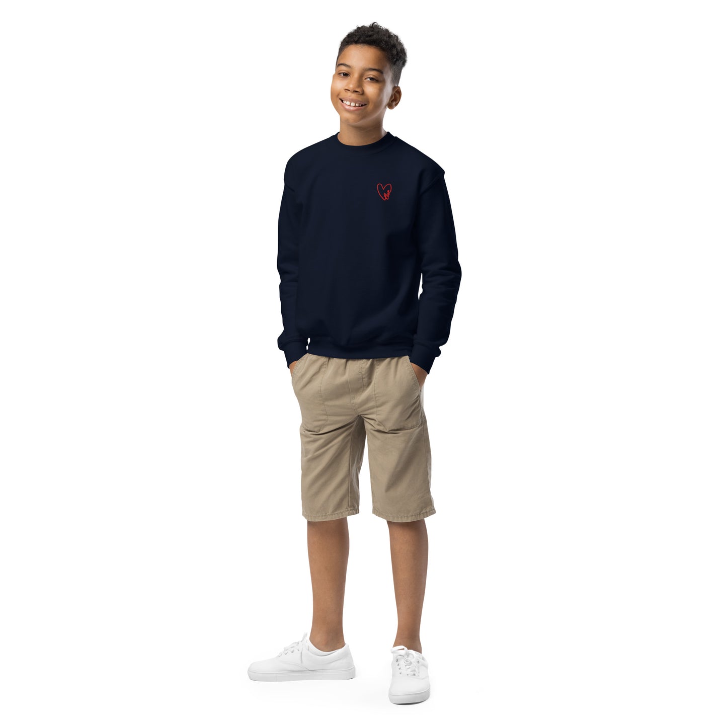 Boy smiling naturally while wearing a navy blue crewneck sweatshirt with a subtle embroidered heart on the chest, styled for a relaxed, everyday look.