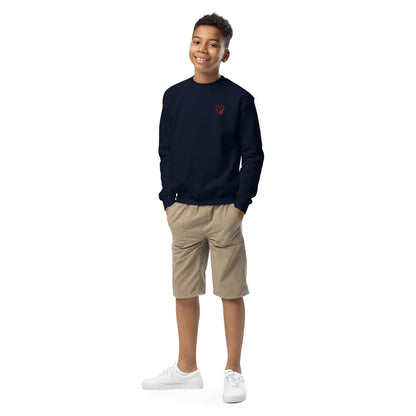 Boy smiling naturally while wearing a navy blue crewneck sweatshirt with a subtle embroidered heart on the chest, styled for a relaxed, everyday look.